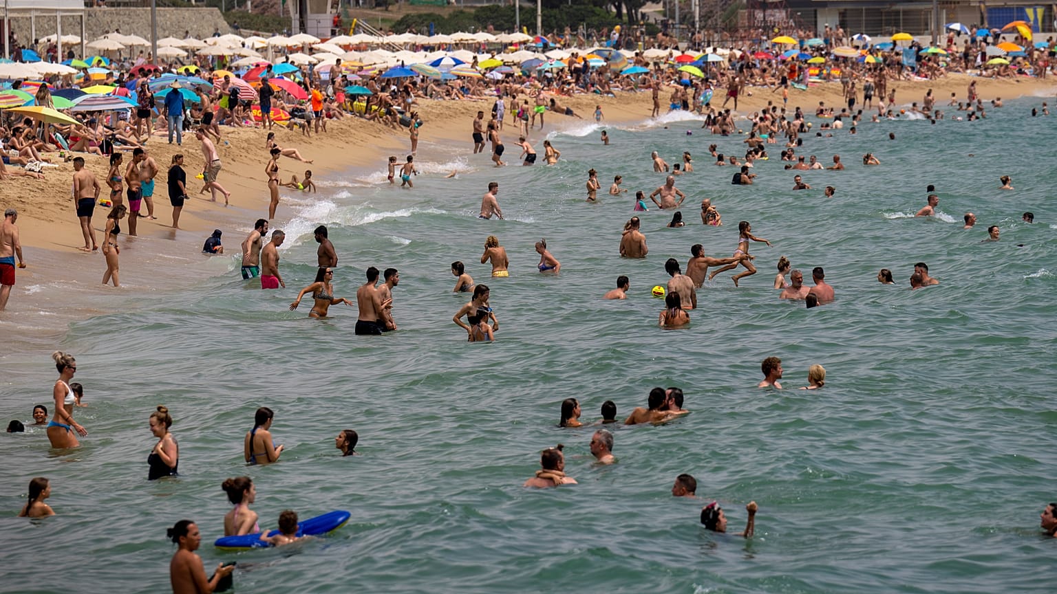 La gente se refresca en el agua durante el clima cálido en una playa de Barcelona, España, el domingo 19 de junio de 2022