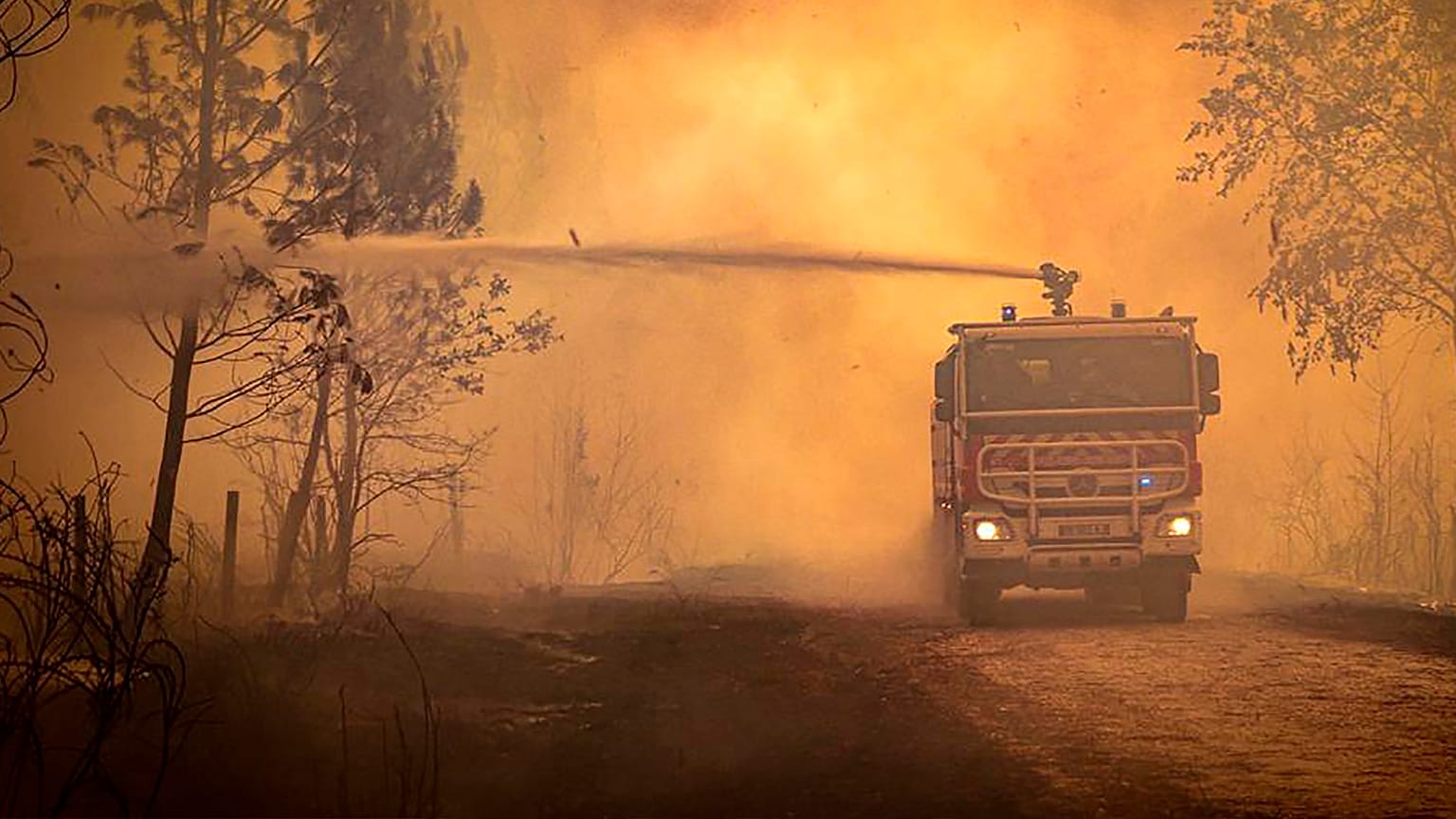 A firefighter truck spraying liquid on a forest wildfire near Landiras, southwestern France on 14 July 2022