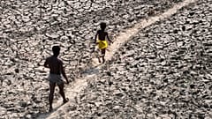 A man and a boy walk across the almost dried up bed of river Yamuna following hot weather in New Delhi, India.
