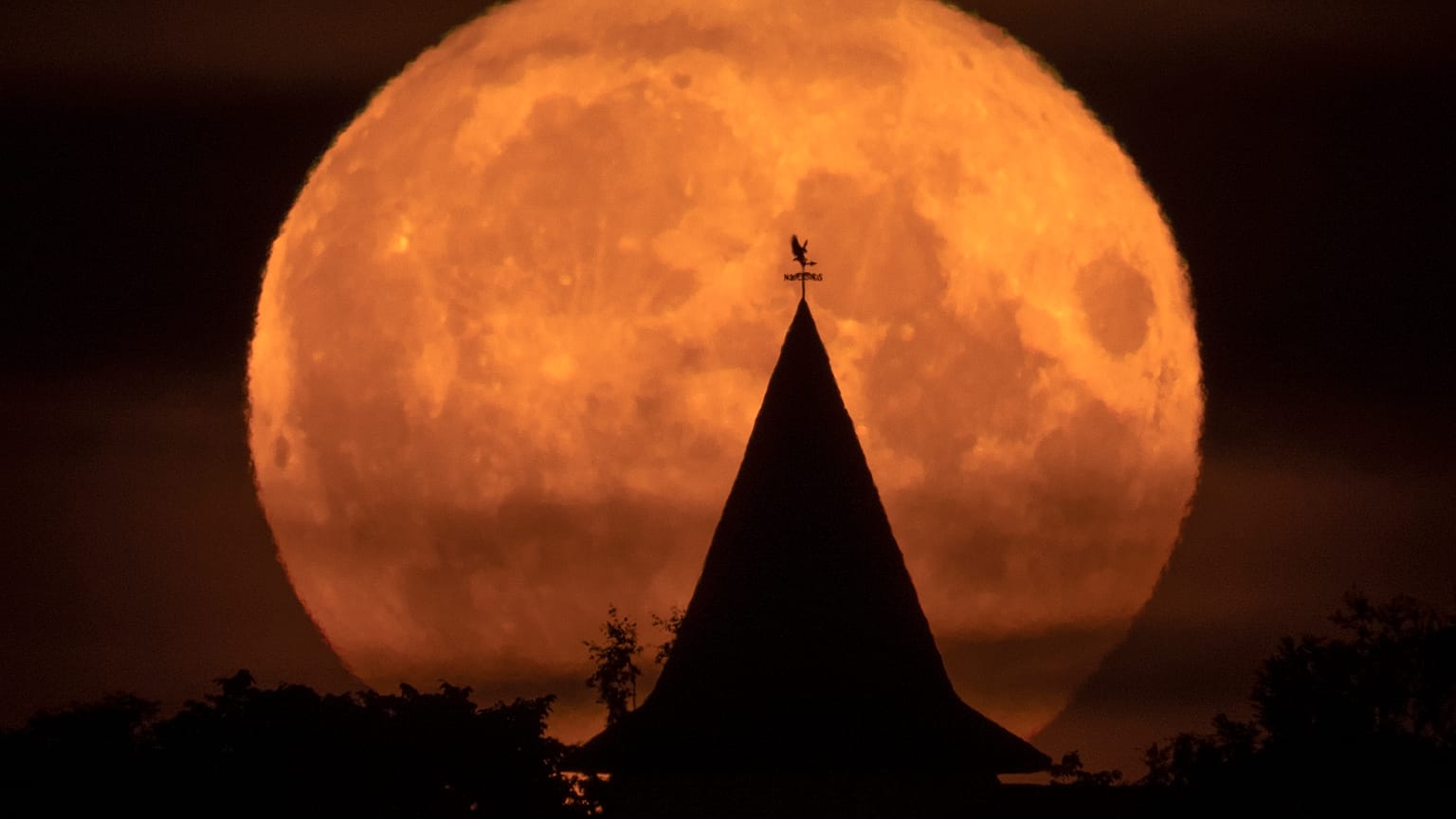 The full moon rises over a private house in the village of Putilovo, 70 kilometeres (43 miles) east of St. Petersburg, Russia, late Wednesday, July 13, 2022.