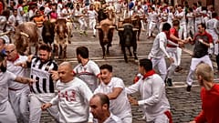 La gente corre por las calles con toros y novillos de lidia durante el último día de los encierros de las fiestas de San Fermín en Pamplona, el jueves 14 de julio de 2022