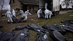 Volunteers load bodies of civilians killed in Bucha onto a truck to be taken to a morgue for investigation, in the outskirts of Kyiv, Ukraine, Tuesday, April 12, 2022. 