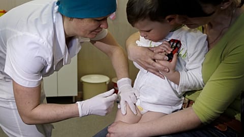 A nurse administers a combined vaccine against diphtheria, whooping cough and tetanus vaccine to a 2-year-old while his mother Inna holds him in Kyiv, Ukraine, April 2013. 