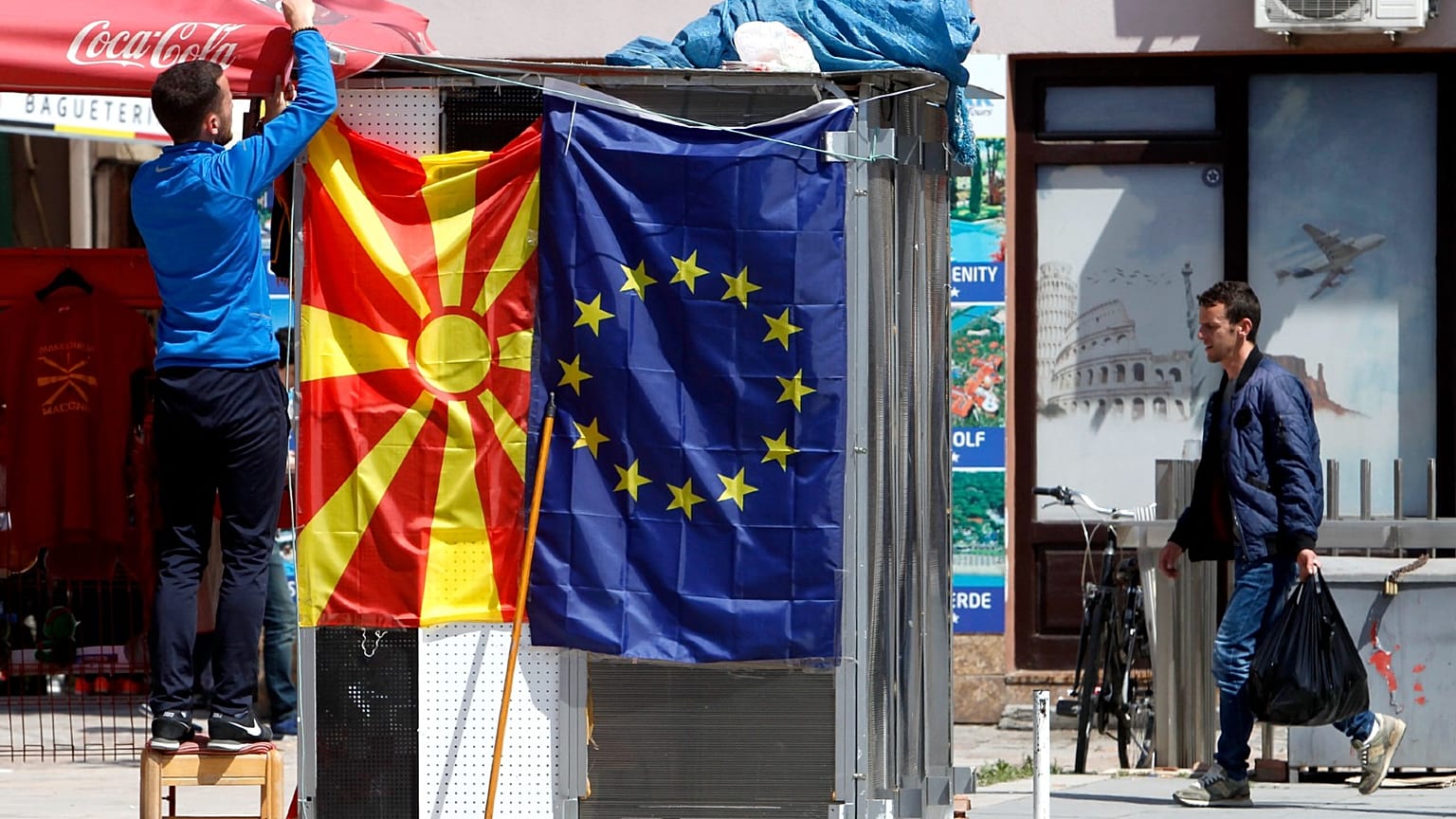 A street vendor fixes a North Macedonia flag next to an EU flag in a street in Skopje, North Macedonia, May 3, 2019. 