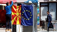 A street vendor fixes a North Macedonia flag next to an EU flag in a street in Skopje, North Macedonia, May 3, 2019. 
