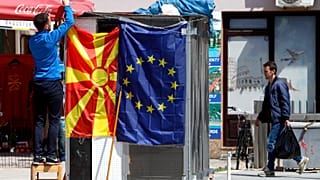 A street vendor fixes a North Macedonia flag next to an EU flag in a street in Skopje, North Macedonia, May 3, 2019.