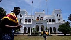 Protesters holding national flags prepare to vacate prime minister Ranil Wickremesinghe's office building with other protesters in Colombo, Sri Lanka, Thursday, July 14, 2022.