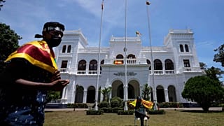 Protesters holding national flags prepare to vacate prime minister Ranil Wickremesinghe's office building with other protesters in Colombo, Sri Lanka, Thursday, July 14, 2022.