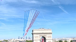 The Patrouille de France (France's fighter jet squadron, Eds.) leaving clouds of blue, white and red smoke flying over La Defense towards the Champs-Elysees.