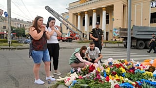 People pray and lay flowers at the site of a Russian shelling on Thursday, in Vinnytsia, Ukraine, Friday, July 15, 2022. Russian missiles killed at least 23 people on Thursday