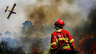 Bombeiro observa avião no combate ao incêndio em Baião, norte de Portugal