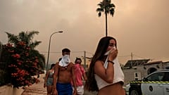 Los residentes se protegen del humo mientras un incendio forestal avanza cerca de una zona residencial en Alhaurín de la Torre, Málaga, España, el 16 de julio de 2022.