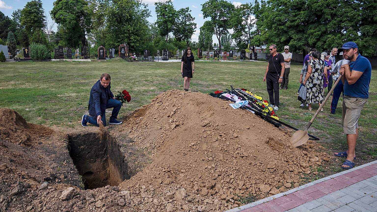Pokrovsk mayor Ruslan Trebushkin, throws dirt on the coffin of 40-year-old Volodymyr Miroshnychenko who was killed on the frontlines of Marinka, 15 July 2022