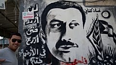 شاب يلتقط صورة بالقرب من جدارية لغسان كنفاني