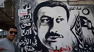 شاب يلتقط صورة بالقرب من جدارية لغسان كنفاني