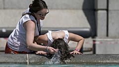 A person wets their hair in a fountain at Trafalgar Square in central London, Tuesday July 19, 2022.