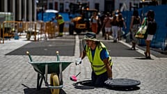 Un ouvrier place des pavés lors d'une journée chaude et ensoleillée à Madrid, en Espagne, lundi 18 juillet 2022.
