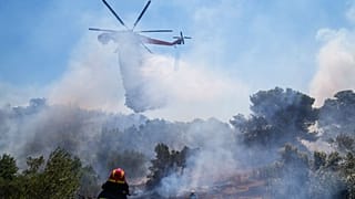 A firefighting helicopter dumps water in the area of Panorama Palinis, east of Athens.