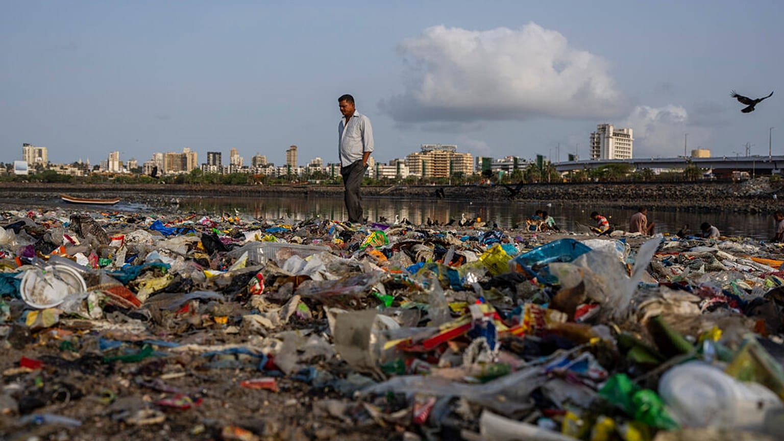 Egy férfi sétál a műanyaggal és más szeméttel borított Arab-tenger partján Mumbai-ban, 2022. június 5-én