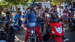 People gather on their electric scooters to spend the late afternoon showing off stunts and racing in Havana, Cuba, Friday, July 15, 2022.