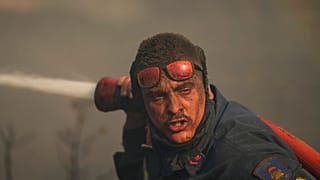 Bombeiro combate incêndio a poucos quilómetros de Atenas, Grécia.