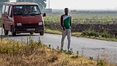 Migrant workers travel in a mini-bus as others take part in a march near Foggia on August 8, 2018.