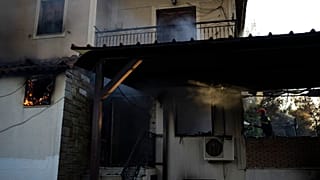 Un bombero trata de extinguir un incendio en una casa cerca de la ciudad de Megara, al oeste de Atenas, Grecia, el miércoles 20 de julio de 2022