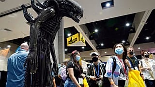 Des visiteurs de la convention observent une réplique taille réelle d'un monstre de la série de films "Alien".