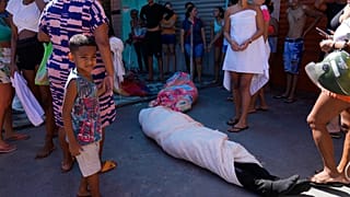 A favela lakói körbecsavart testet állnak körbe a razzia után 