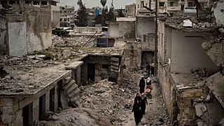 نساء يسرن في حي تضرر بشدة جراء الغارات الجوية في إدلب، سوريا، 12 مارس / آذار 2020.