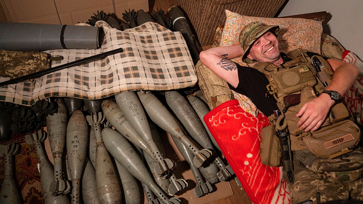 Ukrainian serviceman "Piter" rests on his bed near mortar shells at the frontline in Kharkiv region, Ukraine, Friday, July 22, 2022.