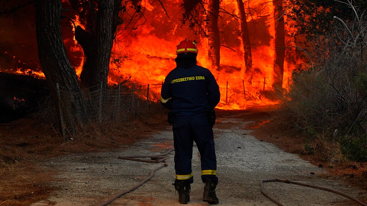 A firefighter tries to extinguish a forest fire near the beach resort of Vatera, on the eastern Aegean island of Lesvos, Greece, on Saturday, July 23, 2022.