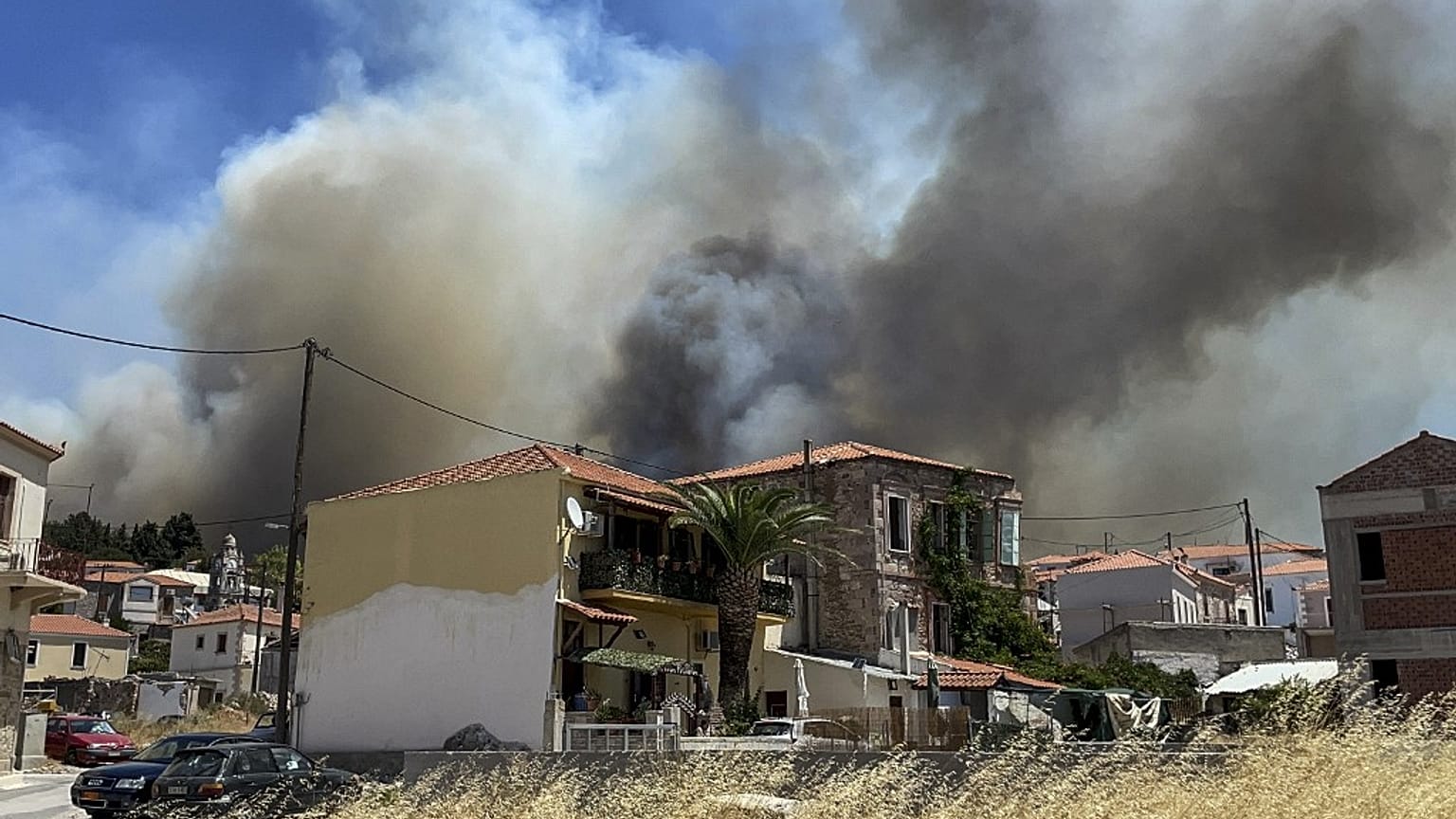 Smoke ascends over the village of Vrisa, in the southern part of the Greek island of Lesbos, as the wildfire burn near tourist resorts for the second day, 24 July, 2022.
