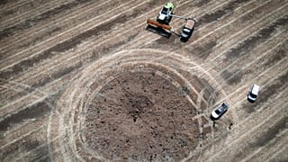 Un agriculteur en train de récolter son champ autour d'un cratère formé par une roquette russe, dans la région de Dnipropetrovsk, en Ukraine, le 4 juillet 2022.