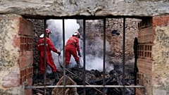 Firefighters douse smouldering rubbles in a burnt house.