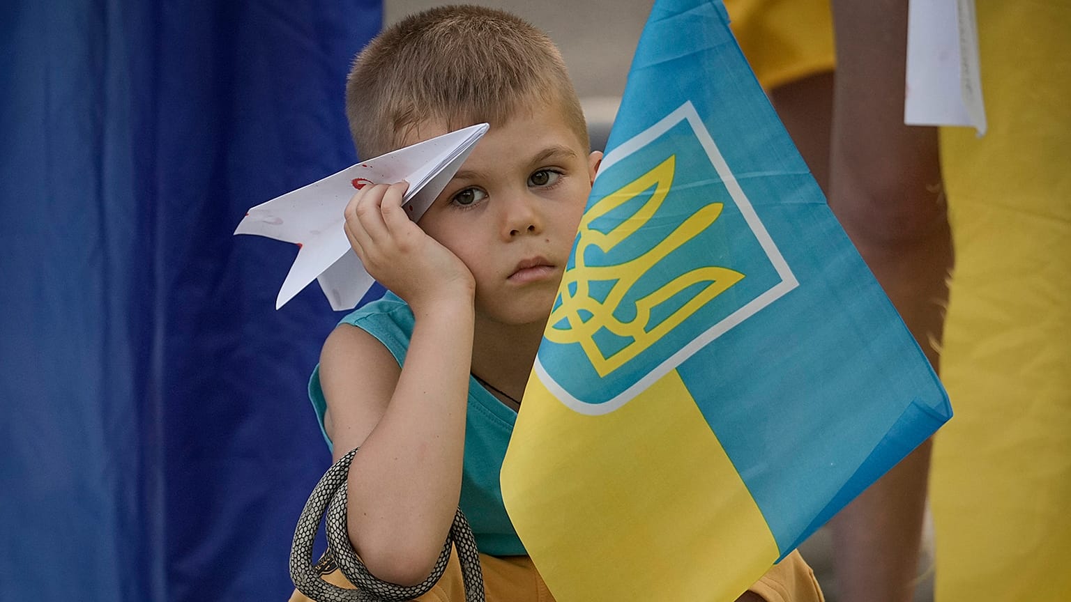 A boy holds a paper plane during a protest by Ukrainian refugees in Bucharest, 23 July 2022