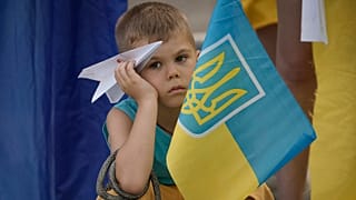 A boy holds a paper plane during a protest by Ukrainian refugees in Bucharest, 23 July 2022