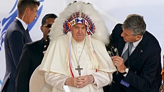 El Papa Francisco se pone un tocado que le fue regalado durante una visita con los pueblos indígenas en Maskwaci, la antigua Escuela Residencial Ermineskin