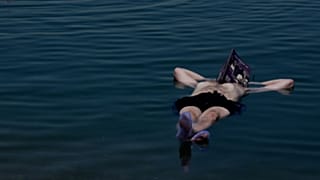 Jury member floating on the Dead Sea, reading the festival catalog, July 25, 2022.