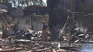 Firefighters work at a damaged residential building following Russian shelling on the outskirts of Odesa, 26 July 2022