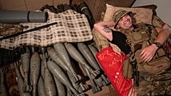 Ukrainian serviceman "Piter" rests on his bed near mortar shells at the frontline in Kharkiv region