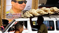 بائع خبز مصري يركب دراجته تحت لافتة عملاقة تدعم المرشح الرئاسي عبد الفتاح السيسي في القاهرة، مصر، الجمعة 18 أبريل / نيسان 2014