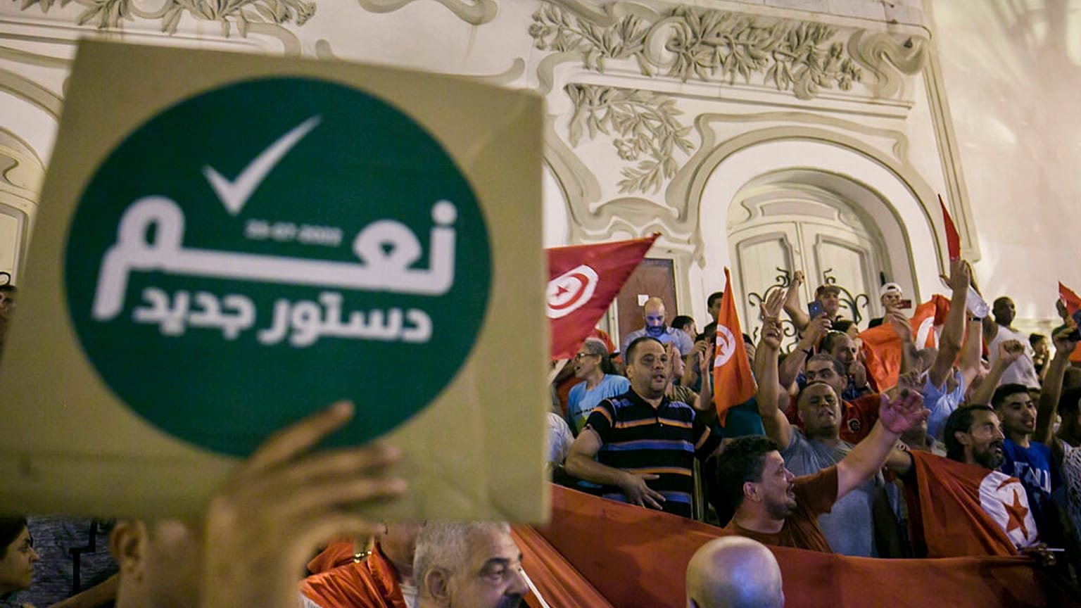 تونسي يحمل لافتة كتب عليها "نعم للدستور الجديد" احتفالا باستطلاعات الرأي التي تشير إلى التصويت لصالح الدستور الجديد، في تونس العاصمة، الإثنين 25 يوليو / تموز 2022