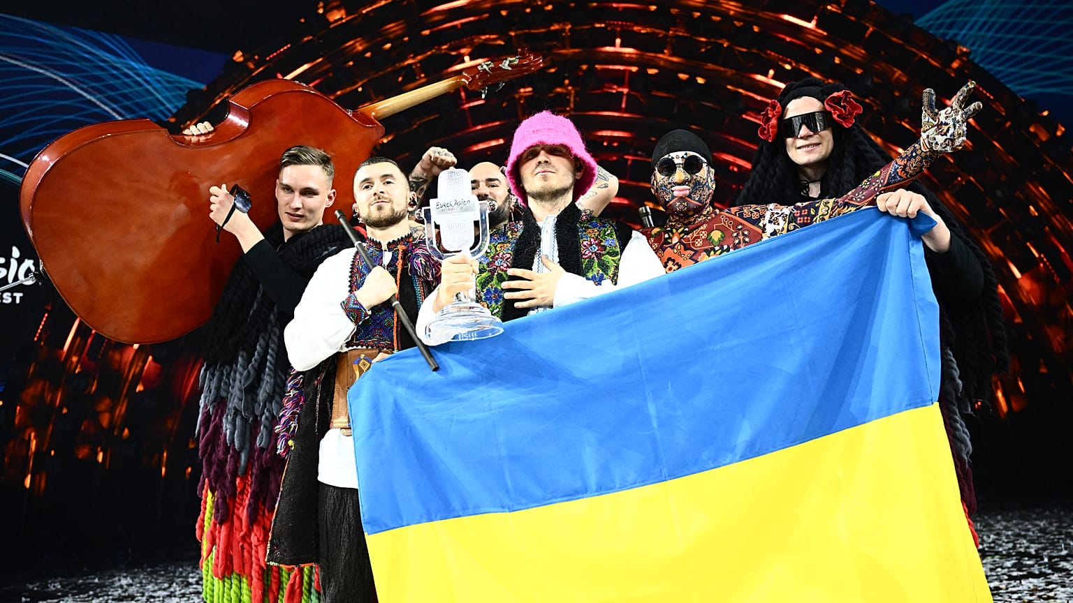 Kalush Orchestra pose onstage with the winner's trophy and Ukrainian flags after winning the Eurovision Song Contest 2022