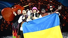 Kalush Orchestra pose onstage with the winner's trophy and Ukrainian flags after winning the Eurovision Song Contest 2022