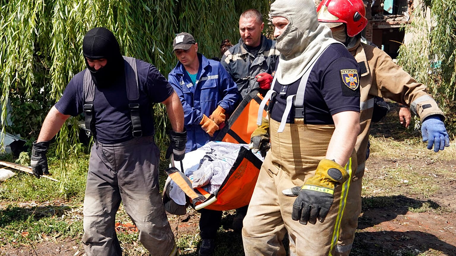 Rescuers move a covered body of a woman killed by Russian missile attack on Monday in Chuhuiv, Kharkiv region, Ukraine, Tuesday, July 26, 2022.