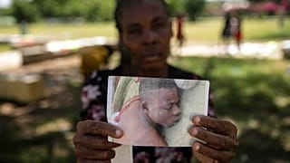 Una mujer muestra la foto de su hijo muerto, víctima de la guerra de las bandas