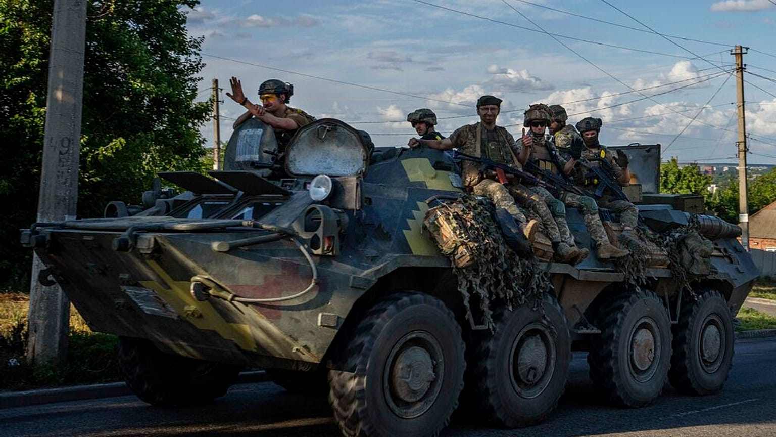 Ukrainian soldiers ride a tank on road to Kherson