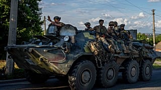 Ukrainian soldiers ride a tank on road to Kherson