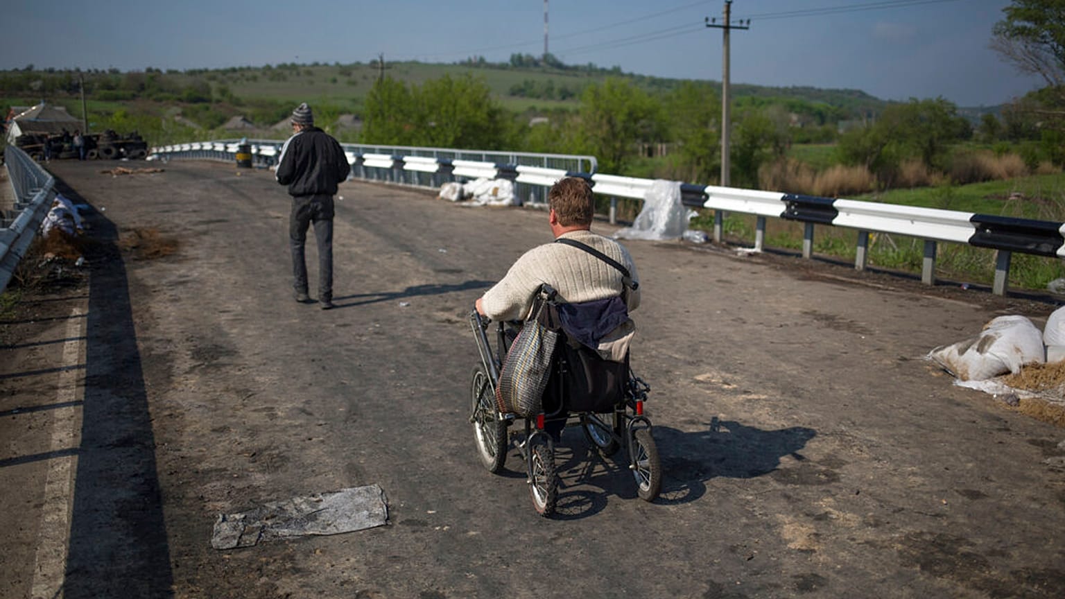 A disabled person goes over the bridge on a wheelchair at a pro-Russian insurgent checkpoint that has been used to block access to a road leading to Slovyansk, Ukraine. 